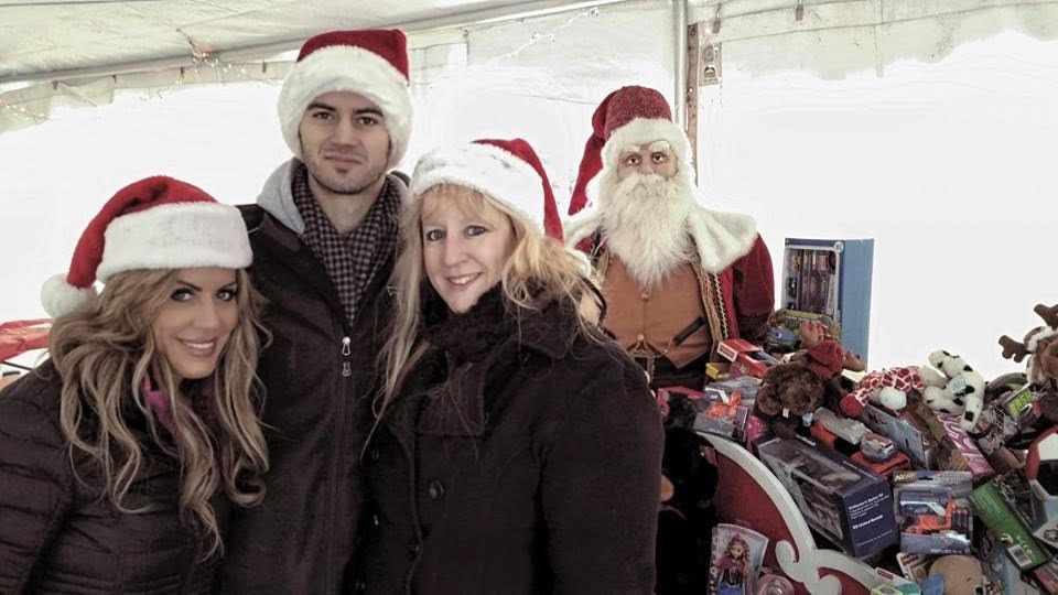 Bryce at Toys for Tots event with volunteers in Santa hats